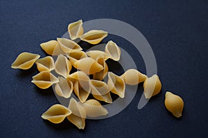 Raw conchiglie pasta on black background