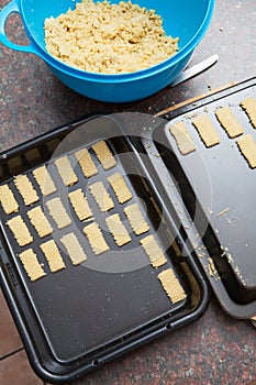 Raw cookie dough being cut and packed onto baking tray