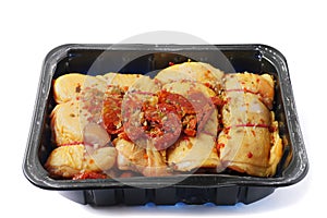 Raw corn fed chicken stuffed thighs wit herbs in a black plastic tray. The product has pronounced yellow color and special taste.