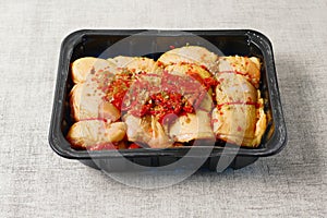 Raw corn fed chicken stuffed thighs wit herbs in a black plastic tray. The product has pronounced yellow color and special taste.