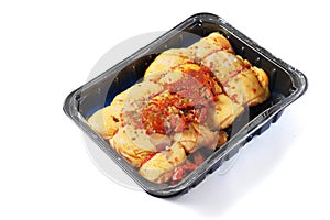 Raw corn fed chicken stuffed thighs wit herbs in a black plastic tray. The product has pronounced yellow color and special taste.