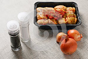 Raw corn fed chicken stuffed thighs wit herbs in a black plastic tray. The product has pronounced yellow color and special taste.