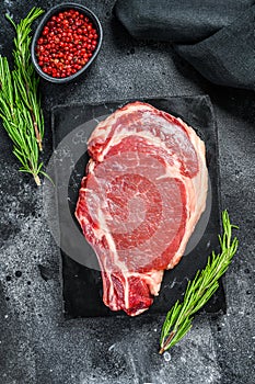 Raw cowboy steak. Marble beef meat on the bone ribeye. Black background. Top view