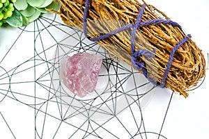 Raw crystal healing rose quartz and white sages herb sticks for clearing negative energy on Metraton cube. Mind and soul spirit.