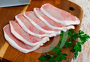 Raw cut pork fillet and parsley on wooden background