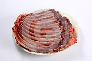 Raw deer ribs on a white plate, white background. Meat of wild animals