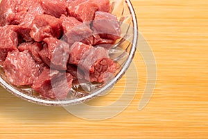 raw diced beef meat in a glass plate on cutting board