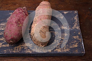 Raw dirty sweet potatoes, yam on wooden rustic brown table. Farm harvest, organic vegetables, shop local, delecious tasty vegan