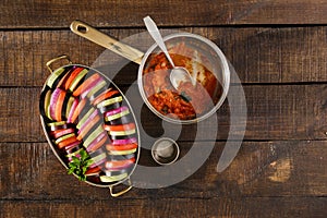 Raw dish ratatouille in pan on wooden table, top view