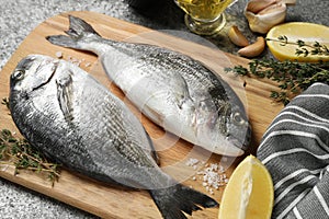 Raw dorada fish and ingredients on table