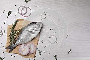 Raw dorado fish, spices and onion on white wooden table, flat lay