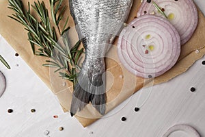 Raw dorado fish, spices and onion on white wooden table, flat lay