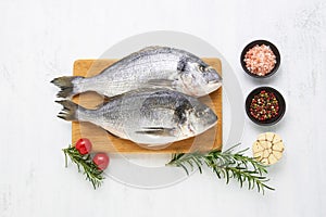 Raw dorado fish with spices on a wooden cutting board on a white background. Mediterranean seafood concept