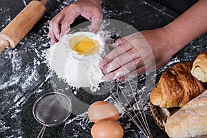 Raw dough for bread with ingredients on black background, male h