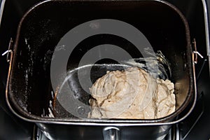 Raw dough in bread pan of electric bread maker