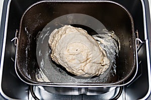 Raw dough in bread pan of electric bread maker
