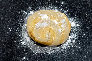 Raw dough for bread or pizza on a black background, close-up, top view. Making homemade baking dough