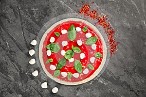 Raw dough for pizza with red sauce and ingredients on table, top view