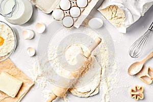 Raw dough ready for kneading on white table. Bakery ingredients, eggs, flour, butter. Shapes for making cookies.