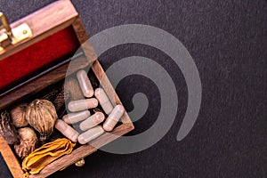 Raw dried spices and herbs with ayurvedic medicines in a wooden basket on a black surface. Ayurvedic medicines concept