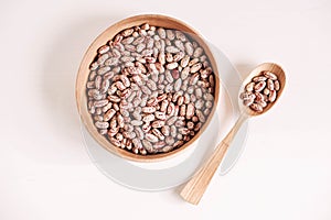 Raw dry beans in a wooden bowl with a spoon on a white background. Top view. Copy, empty space for text