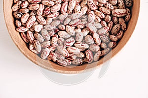 Raw dry beans in a wooden bowl on a white background. Top view. Copy, empty space for text