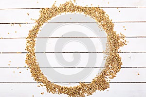 Raw dry green lentil seeds on white wood background