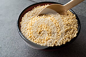 Raw Dry Organic Couscous in a Bowl with Wooden Spoon / Turkish Kuskus.