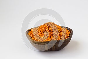 Raw, Dry Red Lentil Heap in a wooden bowl on white surface with copy space