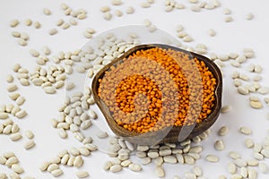 Raw,Dry Red Lentil in a wooden shape bowl on white surface with white beans.