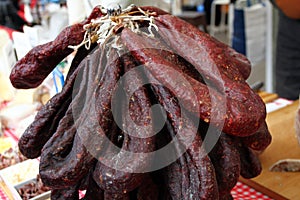 Raw dry salami hangs. Pile of dry salamis hangs. Dry meat background texture. Lukanka, sudjuk. Traditional food. Flat sausages. bu