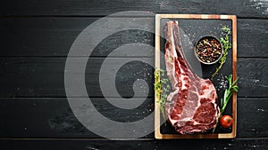 Raw dry steak tomahawk on a black background. Steak Cowboy. Barbecue. Top view.