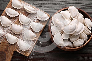 Raw dumplings (varenyky) on brown wooden table, flat lay