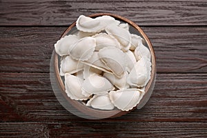 Raw dumplings (varenyky) on brown wooden table, top view