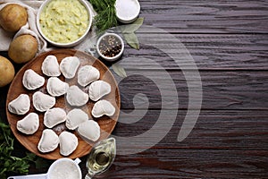 Raw dumplings (varenyky) and ingredients on brown wooden table, flat lay. Space for text