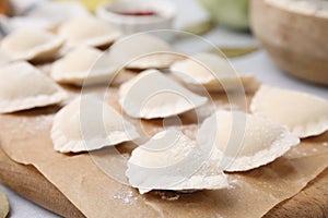 Raw dumplings varenyky with tasty filling on light grey table, closeup