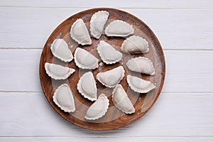 Raw dumplings (varenyky) on white wooden table, top view