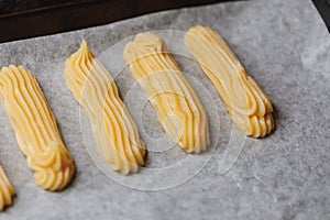 Raw eclairs choux pastry on the baking tray