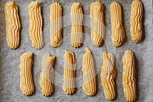 Raw eclairs choux pastry on the baking tray
