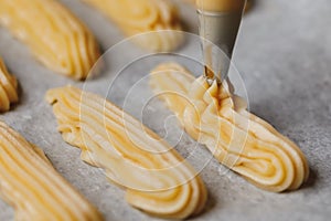 Raw eclairs choux pastry on the baking tray