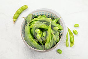 Raw edamame soya beans with salt and sauce on light gray background