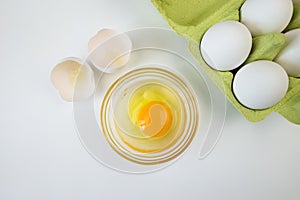Raw egg bowl and eggs in a tray on a white
