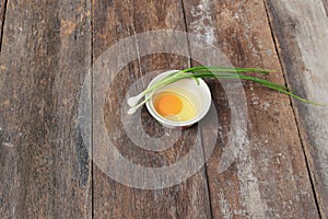 Raw egg in a bowl selective focus and onion on wooden table