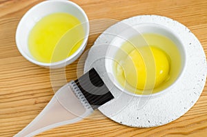 Raw egg and olive oil in a small ceramic bowls for preparing homemade face and hair masks. Ingredients for diy cosmetics.