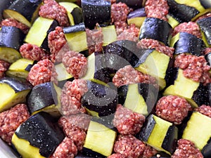 Raw eggplant and minced meat cubes arranged for a traditional casserole