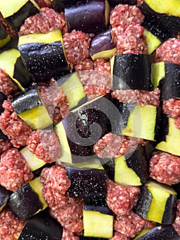 Raw eggplant and minced meat cubes arranged for a traditional casserole