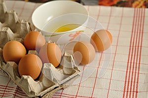 Raw eggs in box and egg yolk in plate
