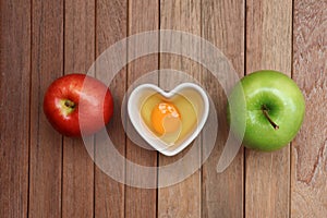 Raw eggs are in a heart shaped container for preparing cooking  with Red apple  and Green apple on a wooden  background texture