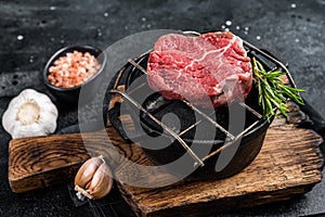 Raw fillet mignon beef steak on a grill with herbs. Black background. Top view