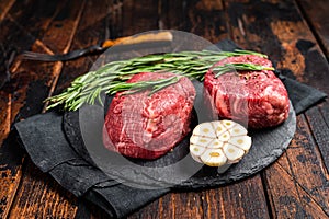 Raw Fillet Mignon Beef steak with herbs and garlic, marble meat. Wooden background. Top view